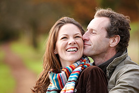 Couple smiling outdoors in colorful scarf.