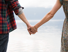 Couple holding hands by the water.