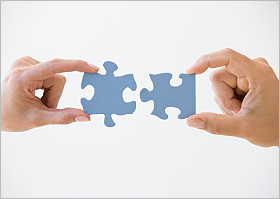 Hands holding two blue puzzle pieces.